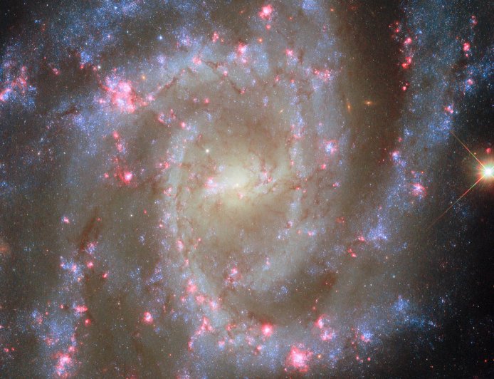 哈勃再秀宇宙美景：3500 万光年外螺旋星系粉色星云“绽放”